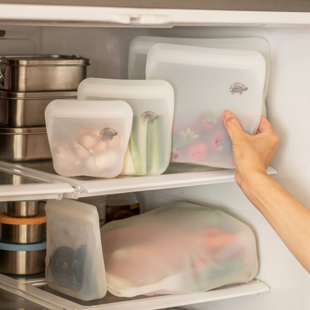 Hand pulling out strawberries in medium Silicone Zip Sealers from fridge.